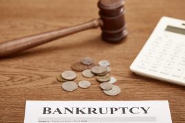 selective focus of bankruptcy form, gavel, calculator and coins on brown wooden table